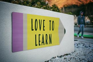 love to learn pencil signage on wall near walking man by Tim Mossholder courtesy of Unsplash.