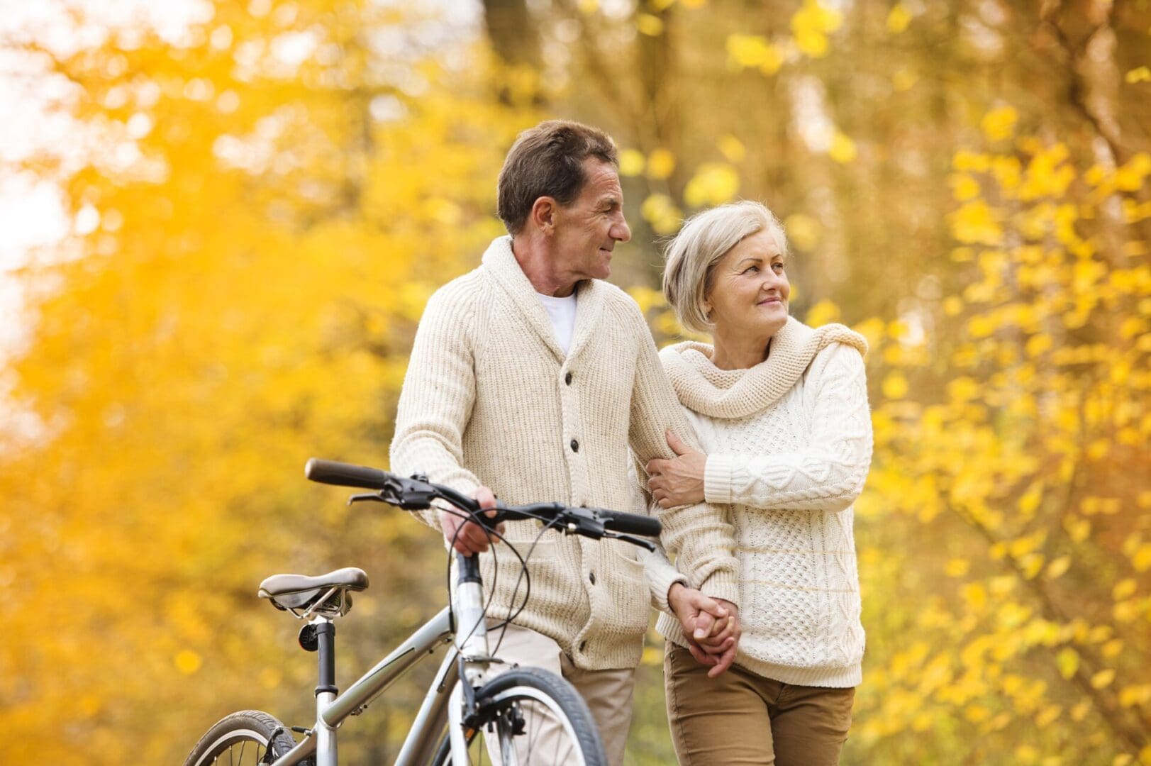 A man and woman holding hands while standing next to a bike.