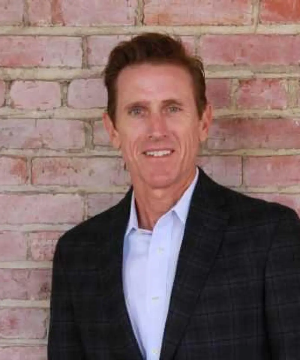 A man in a suit standing next to a brick wall.